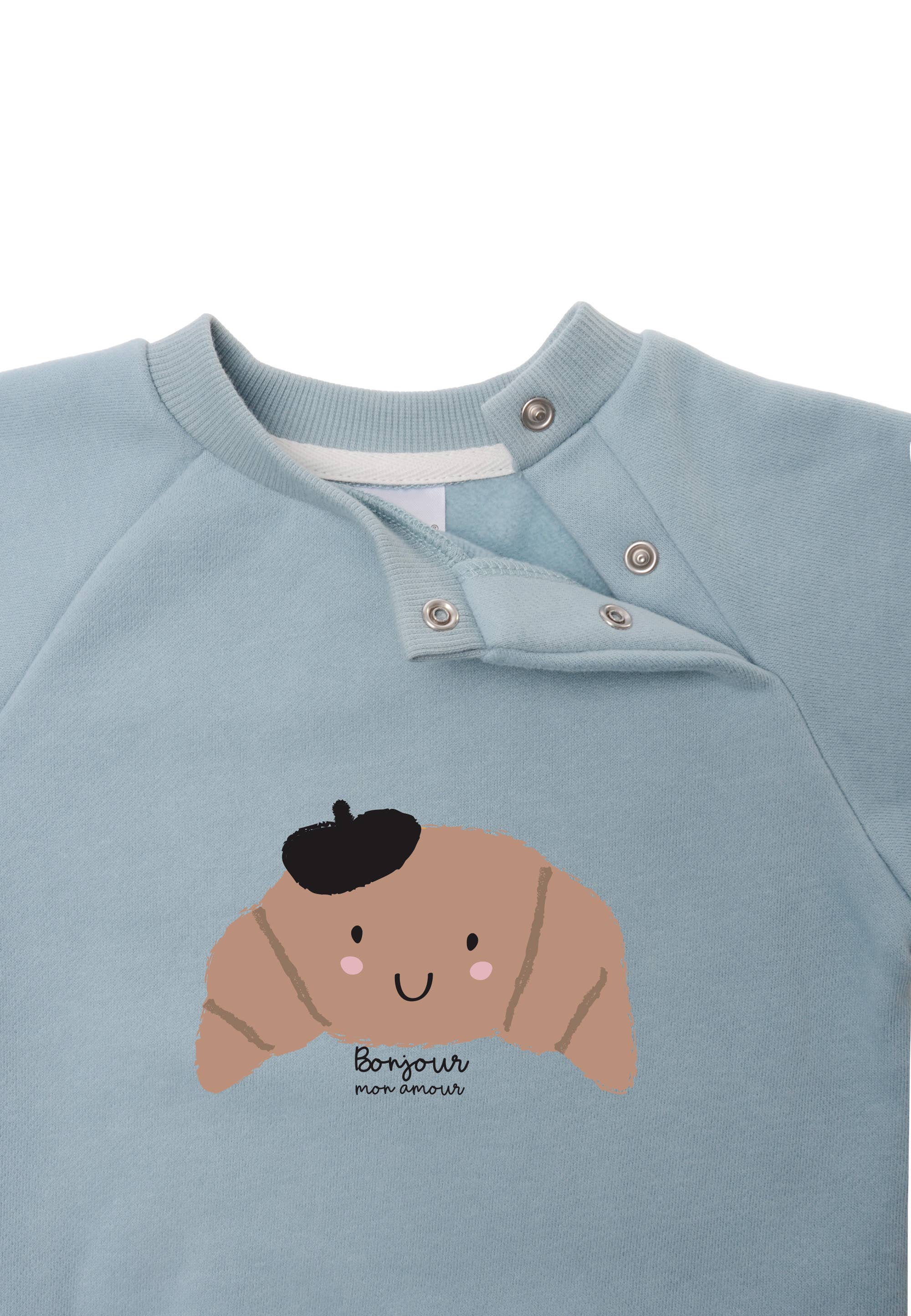 Frisse lichtblauwe sweater met speelse croissant-illustratie
