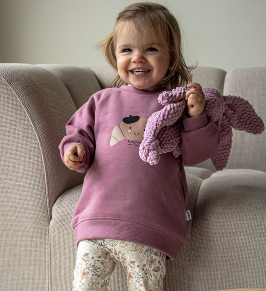 meisje in mauve roze sweater met croissant afbeelding